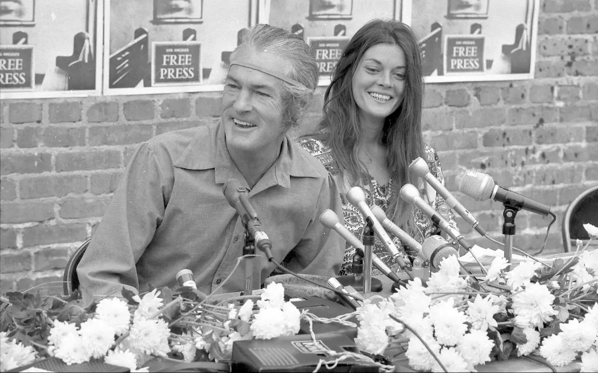 Timothy Leary and Rosemary Woodruff at a press conference decorated with flowers and microphones